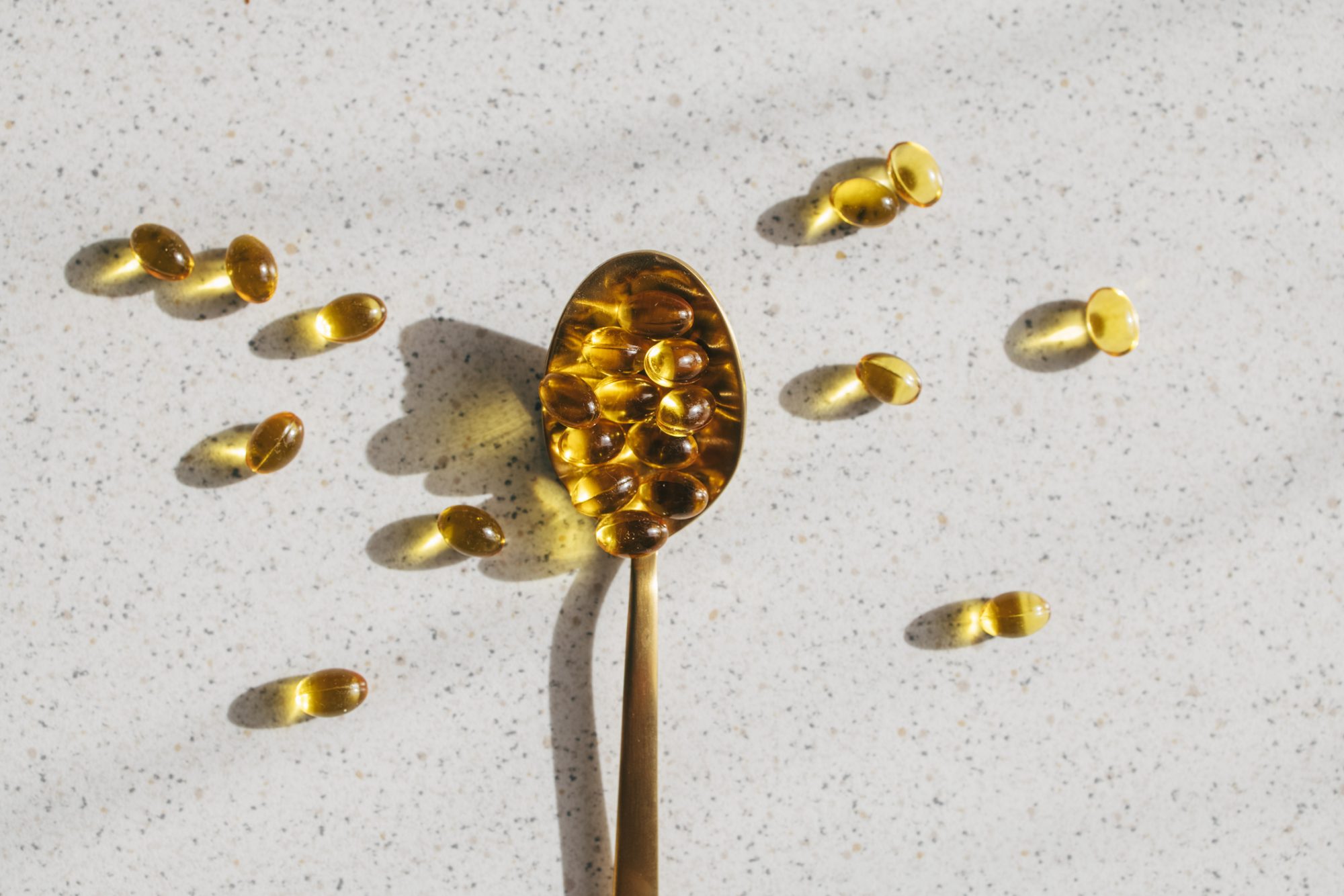 Spoonful of Vitamin D Supplements on a Grey Table, Overhead Shot