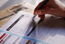 Stock image showing a woman’s hand filling in a postal ballot / voting form.