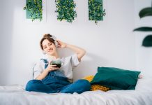 Woman with closed eyes listen music and enjoy cup of coffee or tea. Calm female spend free time at home enjoy favorite song with wireless modern headphones. Pastime weekend relax, no stress concept