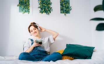 Woman with closed eyes listen music and enjoy cup of coffee or tea. Calm female spend free time at home enjoy favorite song with wireless modern headphones. Pastime weekend relax, no stress concept