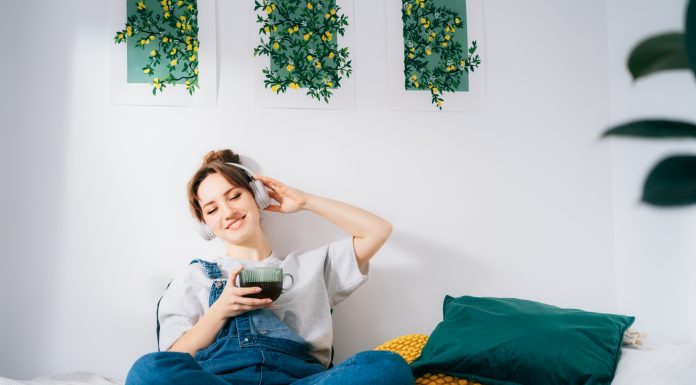 Woman with closed eyes listen music and enjoy cup of coffee or tea. Calm female spend free time at home enjoy favorite song with wireless modern headphones. Pastime weekend relax, no stress concept