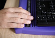 Blind person using computer with braille computer display and a computer keyboard. Blindness aid, visual impairment, independent life concept.
