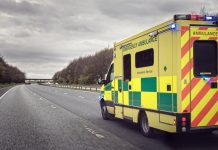 British ambulance responding to an emergency in hazardous bad weather driving conditions on a UK motorway