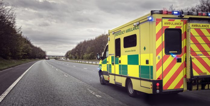 British ambulance responding to an emergency in hazardous bad weather driving conditions on a UK motorway