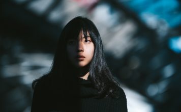 A portrait of a young Asian woman while half of her face is lit by the sun and the other half is in the shadow.