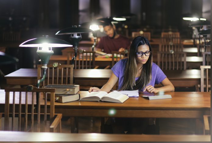 Young vietnamesse woman studying in a library reading room in the evening.