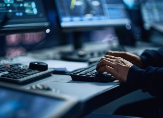 Close Up of a Professional Office Specialist Working on Desktop Computer in Modern Technological Monitoring Control Room with Digital Screens. Manager Typing on keyboard and Using Mouse.