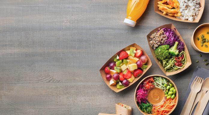 Healthy take away food and drink in disposable eco friendly paper containers on gray wooden background, top view. Fresh salad, soup, poke bowl, vegetable, fruits, chicken wrap and juice.