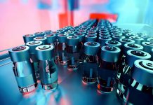 Close-up of medicine glass vials on a pharmaceutical production line, with metal caps and blank labels, moving forward. Industrial background, manufacturing equipment. Teal and orange hues. Digitally generated image. Selective focus.