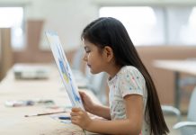 Little girl looking at painting very close