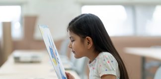 Little girl looking at painting very close