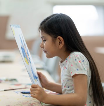 Little girl looking at painting very close