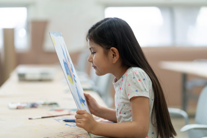 Little girl looking at painting very close