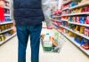 Man holding shopping basket with bread and milk groceries in supermarket