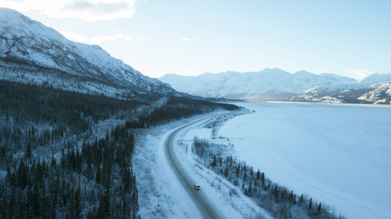 Aerial shot of fields, mountains and forest covered in snow in Whitehouse, Yukon, Canada