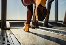 Close up of unrecognizable athletic woman exercising on treadmill in a health club. Copy space.