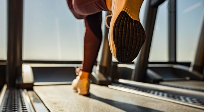 Close up of unrecognizable athletic woman exercising on treadmill in a health club. Copy space.