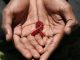 A hand made beaded AIDS symbol in the hands of a black man.