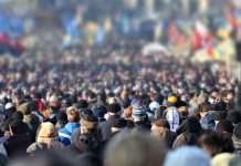 Crowd of anonymous people on street in city center, selective focus