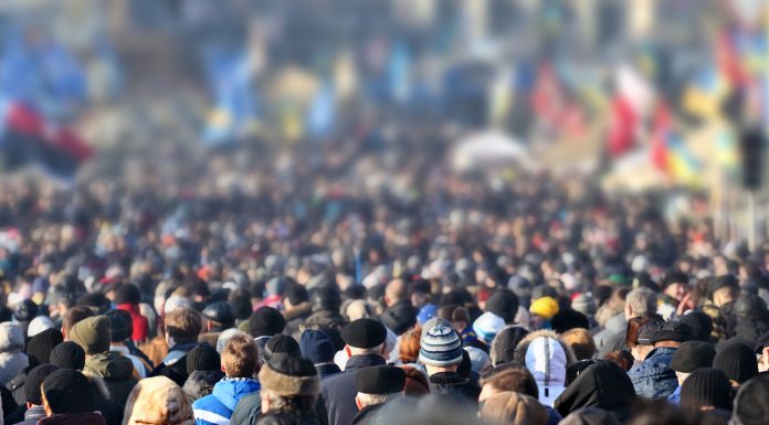 Crowd of anonymous people on street in city center, selective focus