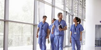 Four healthcare workers in scrubs walking in corridor