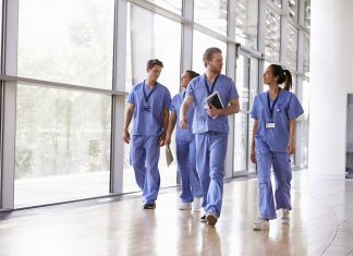 Four healthcare workers in scrubs walking in corridor