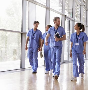 Four healthcare workers in scrubs walking in corridor