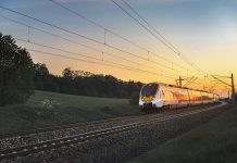 Modern regional train traveling with speed on railway tracks through nature landscape, at sunset, near Schwabisch Hall, Germany.