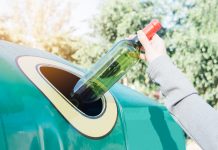 Hand throwing glass bottle in recycling bin