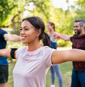 Mixed race woman exercising in park with mature friends