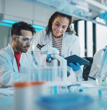 Modern Medical Research Laboratory: Portrait of Latin and Black Young Scientists Using Microscope, Digital Tablet, Doing Sample Analysis, Talking. Diverse Team of Specialists work in Advanced Lab