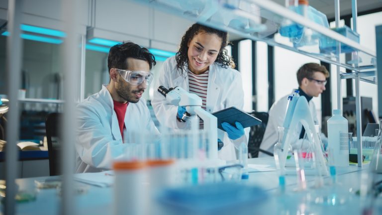 Modern Medical Research Laboratory: Portrait of Latin and Black Young Scientists Using Microscope, Digital Tablet, Doing Sample Analysis, Talking. Diverse Team of Specialists work in Advanced Lab