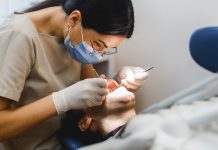 Group portrait of two people, woman dentist making treatment in modern clinic for man. Medical concept photography indoors for dentistry. Dental office, doctor working in clinic with patient.