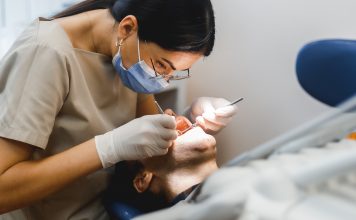 Group portrait of two people, woman dentist making treatment in modern clinic for man. Medical concept photography indoors for dentistry. Dental office, doctor working in clinic with patient.