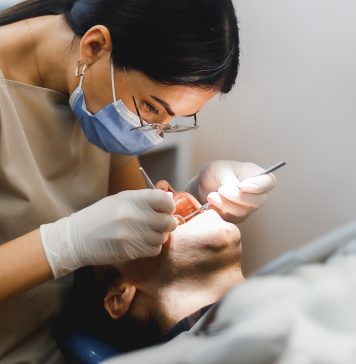 Group portrait of two people, woman dentist making treatment in modern clinic for man. Medical concept photography indoors for dentistry. Dental office, doctor working in clinic with patient.