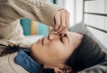 One woman, Japanese woman having headache while lying on bed in her bedroom at home.