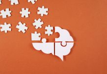 Brain shaped puzzle pieces on red background, mental health crisis