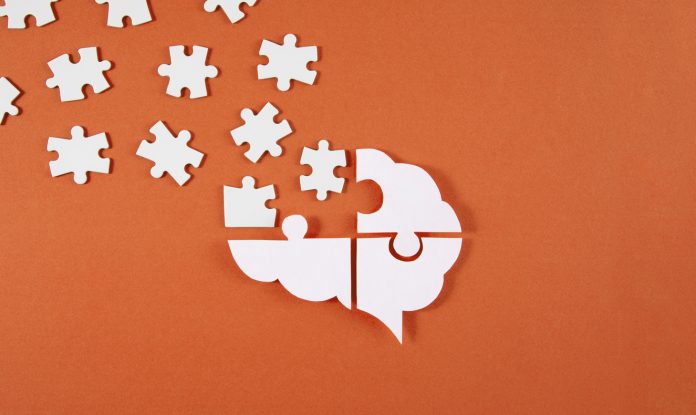 Brain shaped puzzle pieces on red background, mental health crisis