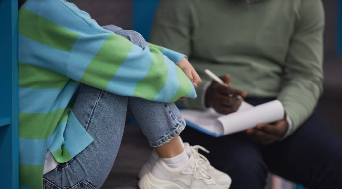 Closeup of stressed teenage girl talking to mental health therapist in session