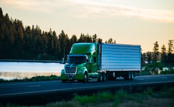 Long-haul semi-truck driving along a scenic stretch of freeway.