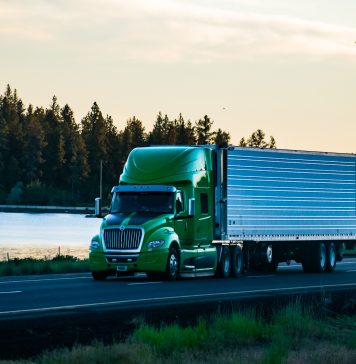 Long-haul semi-truck driving along a scenic stretch of freeway.