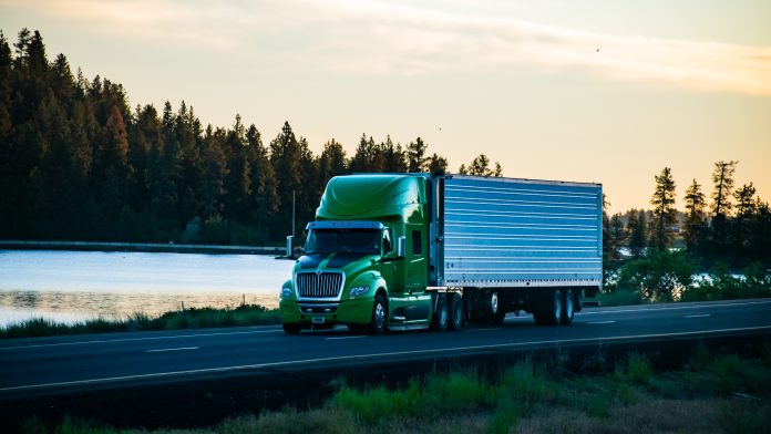Long-haul semi-truck driving along a scenic stretch of freeway.