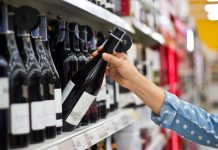 Woman is buying a bottle of wine at the supermarket background