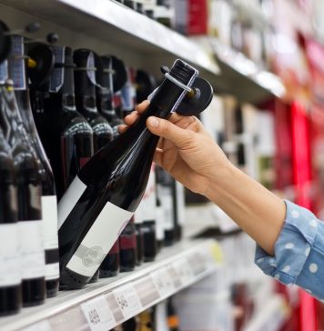 Woman is buying a bottle of wine at the supermarket background