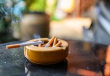 Cigarette burning with smoking on ceramic ashtray