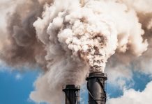 Two industrial chimneys emitting thick clouds of smoke.