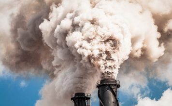 Two industrial chimneys emitting thick clouds of smoke.