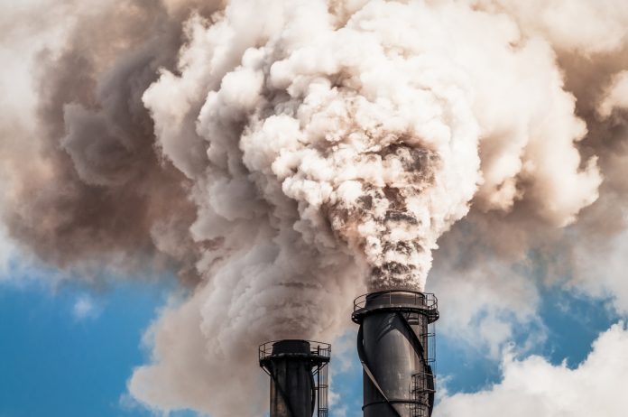 Two industrial chimneys emitting thick clouds of smoke.