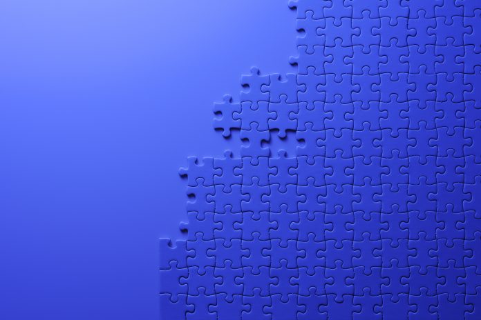 Overhead shot of blue jigsaw puzzle on blue background with copy space.
