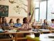 African American schoolgirl raising her hand to answer the question on a class in the classroom.